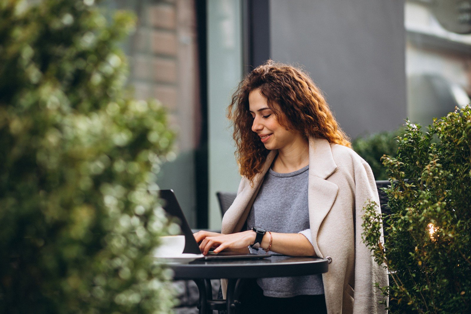 a woman working on her laptop while sitting at a coffee shop