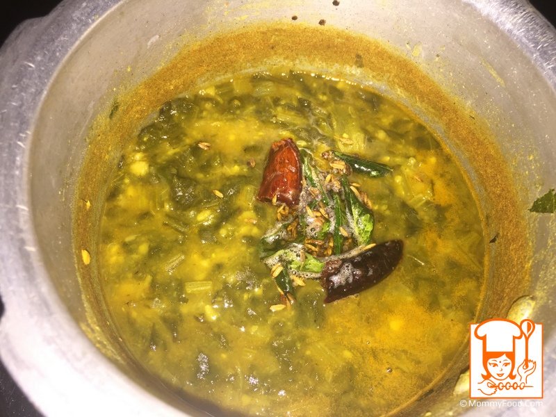 Pouring tempering over the spinach stew