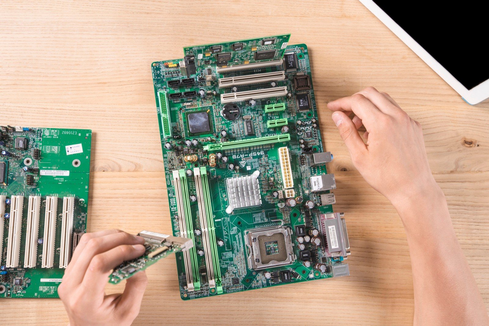 Close-up image of a person working on a computer motherboard, showcasing its various components and intricate design.