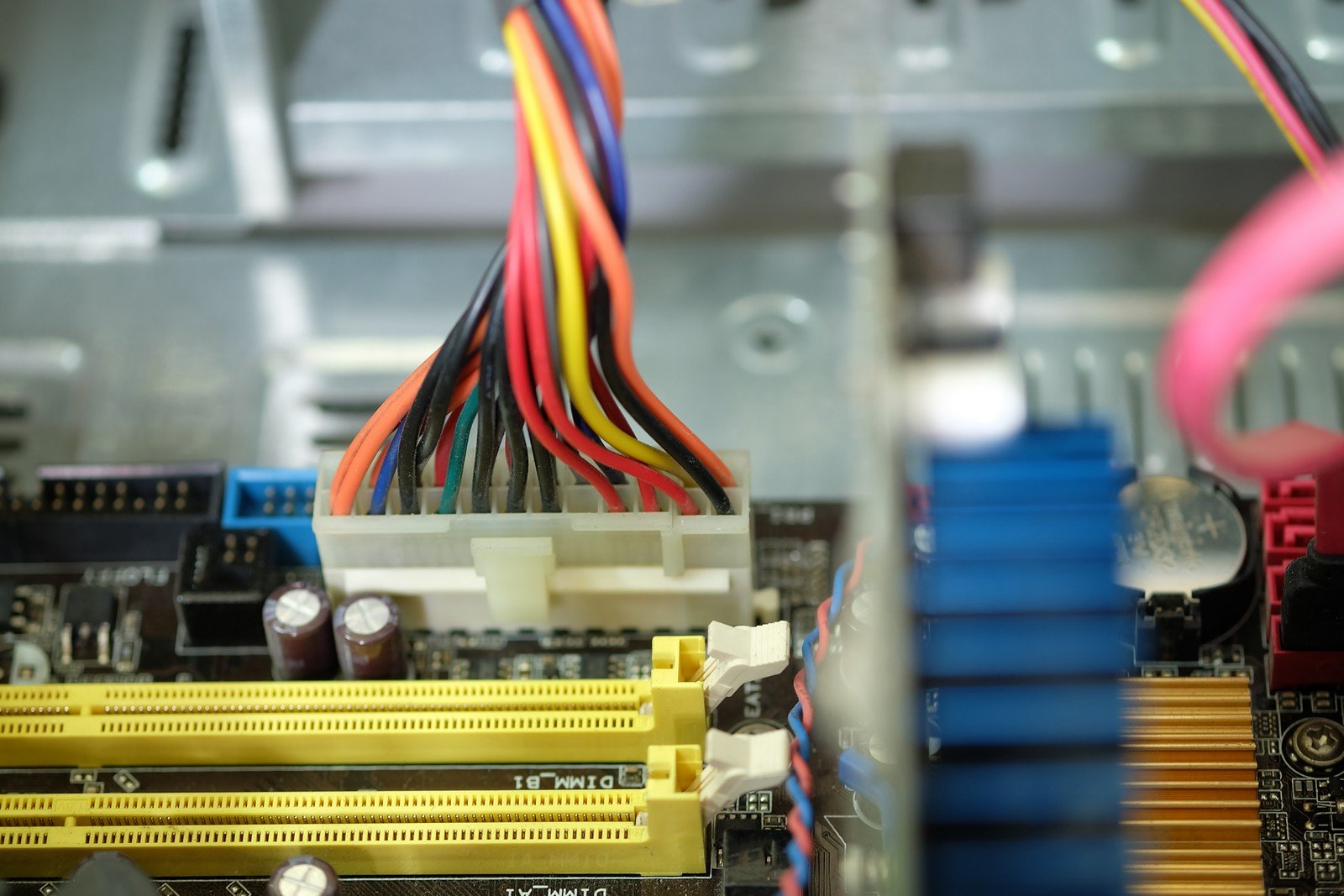 Close-up image of a 24 Pin Power Connector connected to a motherboard, showing its wires and slots in a modern PC setup.